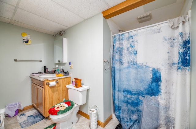 bathroom featuring toilet, vanity, tile patterned floors, and a drop ceiling