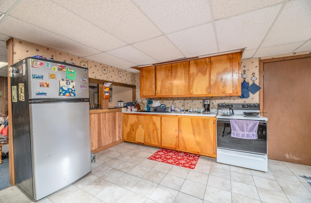 kitchen featuring white range with electric cooktop, stainless steel fridge, and a paneled ceiling