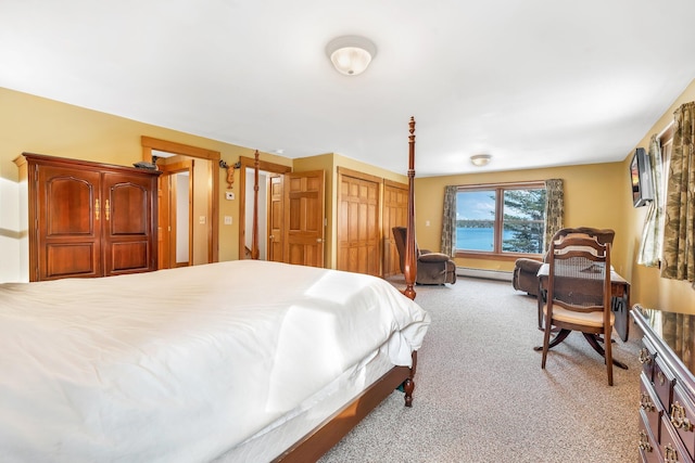 bedroom featuring a baseboard heating unit, multiple closets, and light colored carpet