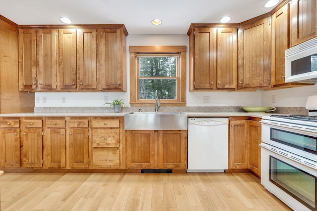 kitchen featuring sink, light hardwood / wood-style flooring, and white appliances