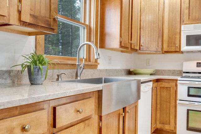 kitchen featuring light stone countertops, sink, and white appliances