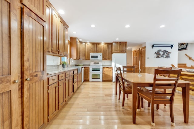 kitchen with sink, white appliances, and light hardwood / wood-style flooring