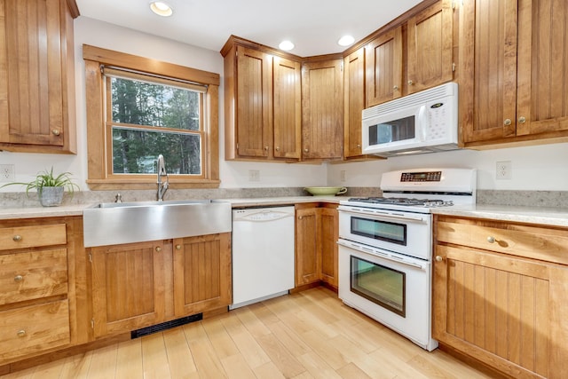 kitchen with light wood-type flooring, sink, and white appliances