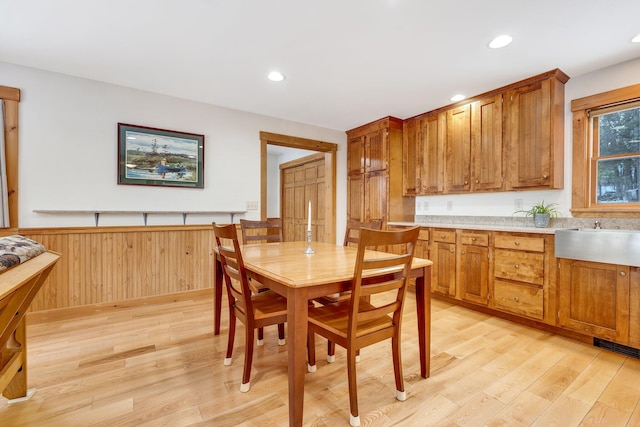 dining room with wood walls, light hardwood / wood-style flooring, and sink