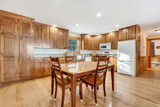 dining room featuring baseboard heating, wood walls, and light wood-type flooring