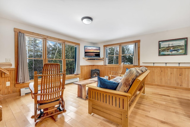 sitting room with light wood-type flooring, a wood stove, and wooden walls