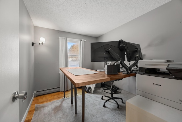 home office with light wood-type flooring, baseboard heating, and a textured ceiling