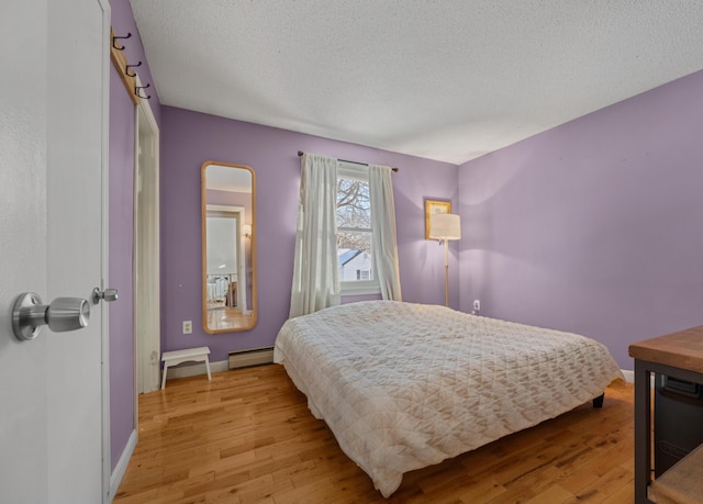 bedroom with a textured ceiling, light hardwood / wood-style flooring, and baseboard heating