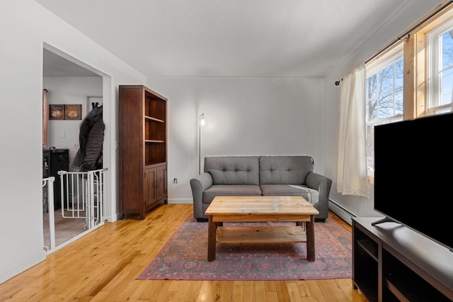 living room with hardwood / wood-style flooring, a textured ceiling, and a baseboard heating unit