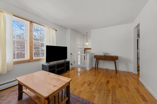 living room with light hardwood / wood-style flooring, a baseboard heating unit, and a textured ceiling