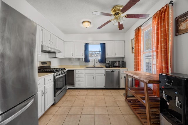 kitchen featuring white cabinetry, stainless steel appliances, sink, a textured ceiling, and light tile patterned flooring