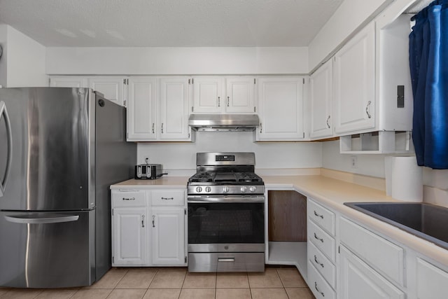 kitchen featuring white cabinets, light tile patterned floors, stainless steel appliances, and a textured ceiling