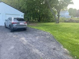 view of parking featuring a lawn and a garage