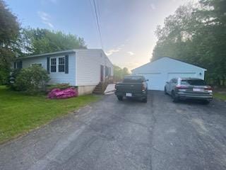 view of side of property with a garage, a lawn, and an outbuilding