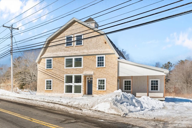 snow covered back of property featuring a gambrel roof