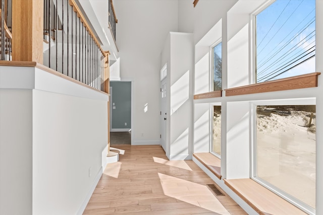 foyer with visible vents, a high ceiling, light wood-type flooring, baseboards, and stairs