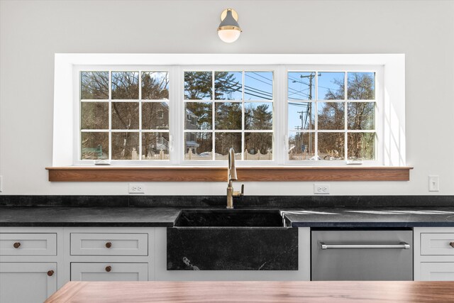 kitchen with dishwasher, dark countertops, a sink, and white cabinets