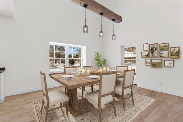 dining area with a high ceiling, light wood-style flooring, and baseboards