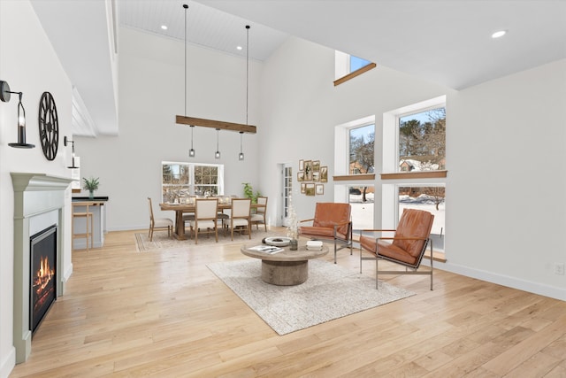 living area with a glass covered fireplace, plenty of natural light, and light wood-style flooring