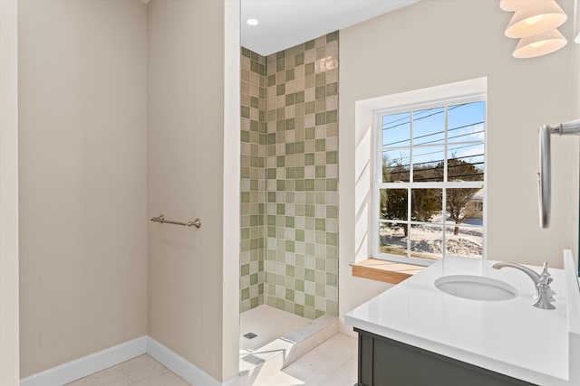 bathroom featuring baseboards, tiled shower, vanity, and tile patterned floors