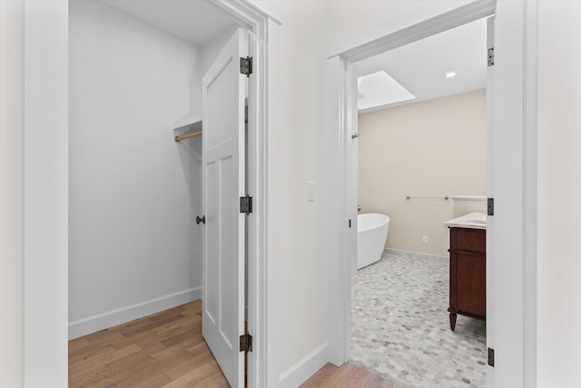 full bathroom featuring a freestanding bath, vanity, baseboards, and wood finished floors