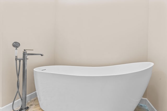 full bath featuring a freestanding tub and baseboards