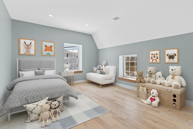 bedroom featuring lofted ceiling, light wood-style flooring, visible vents, and baseboards