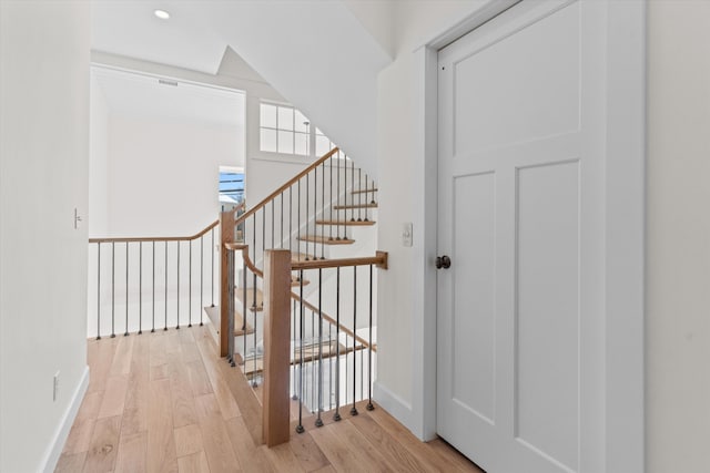 stairway with baseboards, wood finished floors, and recessed lighting