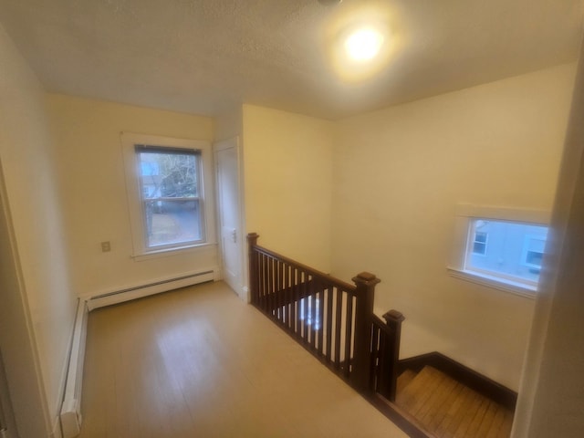 staircase with wood-type flooring and a baseboard heating unit