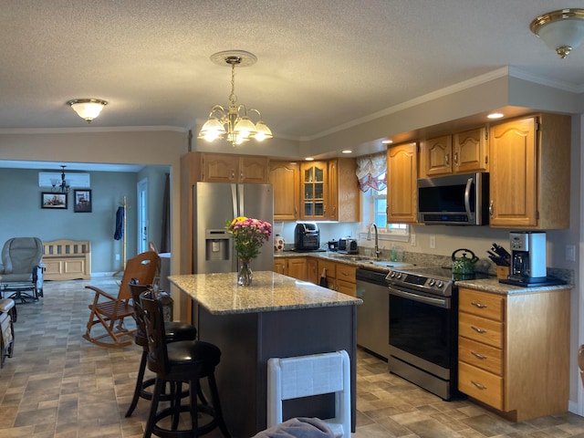 kitchen with appliances with stainless steel finishes, crown molding, pendant lighting, a notable chandelier, and a kitchen island