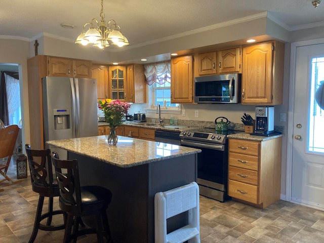 kitchen with an inviting chandelier, crown molding, hanging light fixtures, a kitchen island, and stainless steel appliances