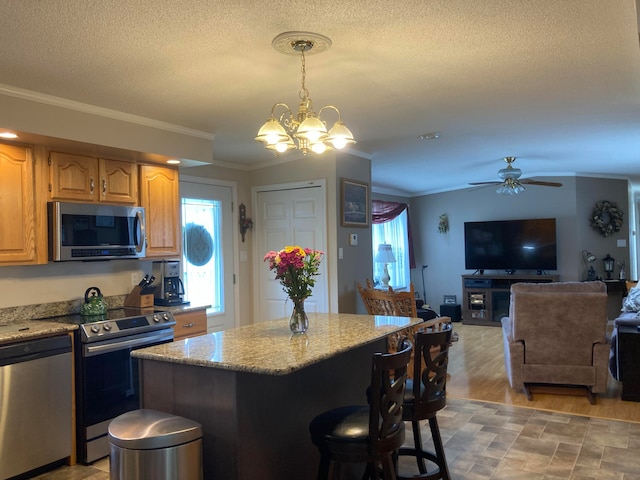 kitchen featuring a center island, stainless steel appliances, ornamental molding, pendant lighting, and light wood-type flooring