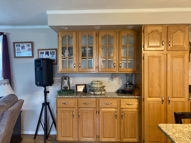 bar featuring a textured ceiling, light stone counters, and crown molding