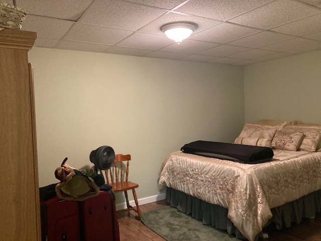 bedroom with wood-type flooring and a drop ceiling