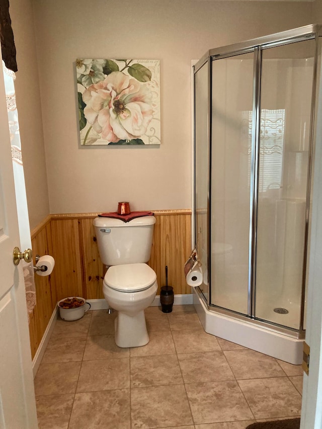 bathroom with tile patterned floors, wooden walls, toilet, and walk in shower