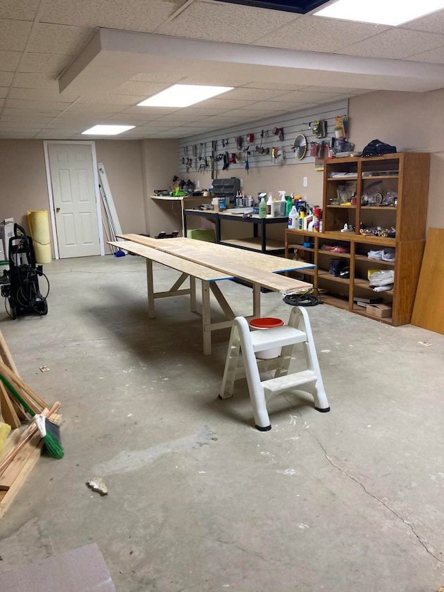 basement featuring a paneled ceiling and a workshop area