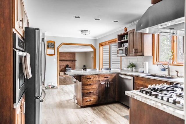 kitchen featuring sink, stainless steel appliances, island exhaust hood, kitchen peninsula, and a kitchen bar