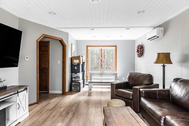 living room featuring a wall mounted AC, light hardwood / wood-style flooring, and wood ceiling