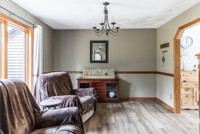 sitting room with light wood-type flooring and an inviting chandelier