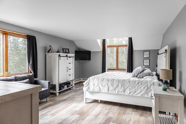 bedroom featuring baseboard heating, a barn door, lofted ceiling, and light wood-type flooring