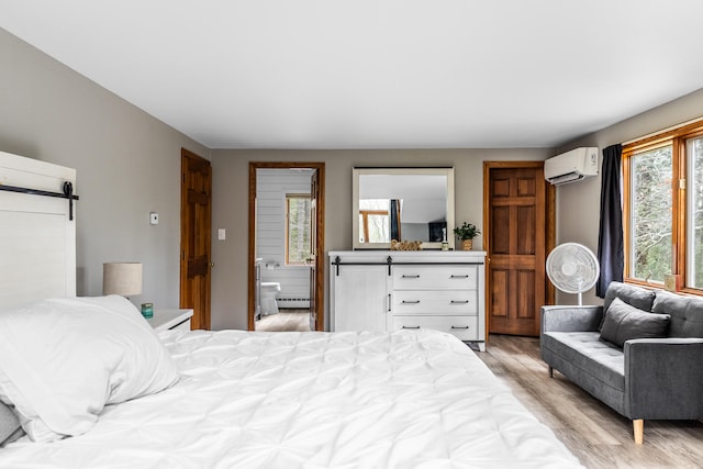 bedroom featuring multiple windows, a barn door, a wall mounted air conditioner, and light wood-type flooring