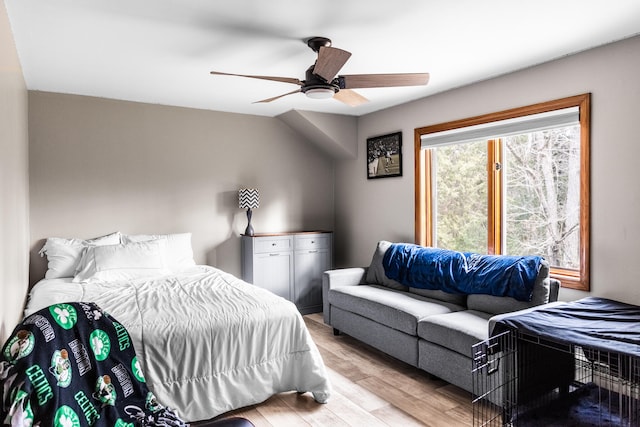 bedroom with ceiling fan, light hardwood / wood-style floors, and vaulted ceiling