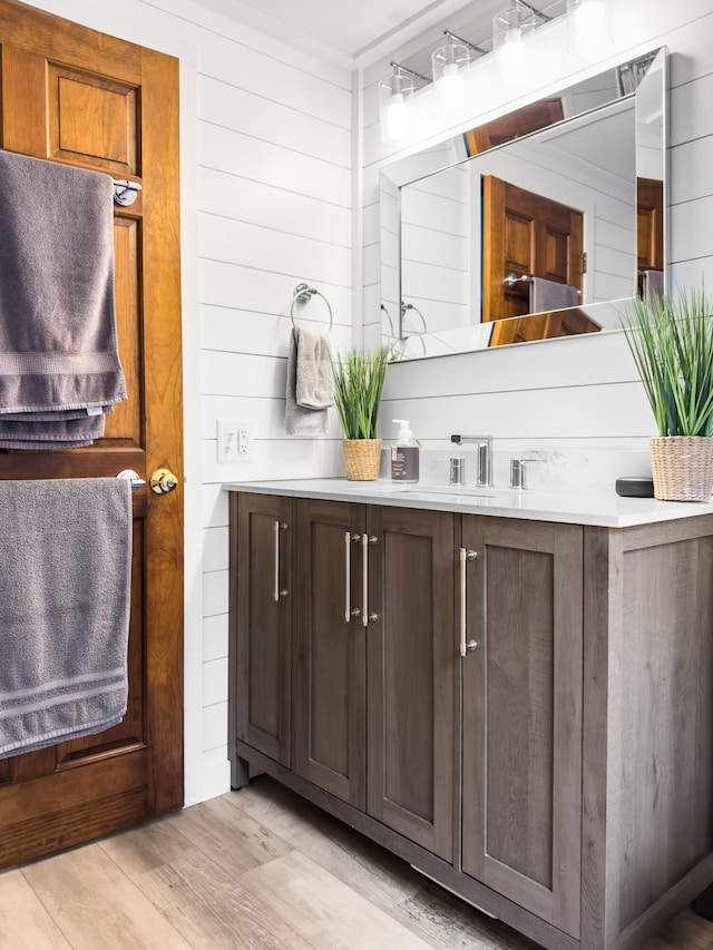 bathroom with wood walls, vanity, and hardwood / wood-style flooring