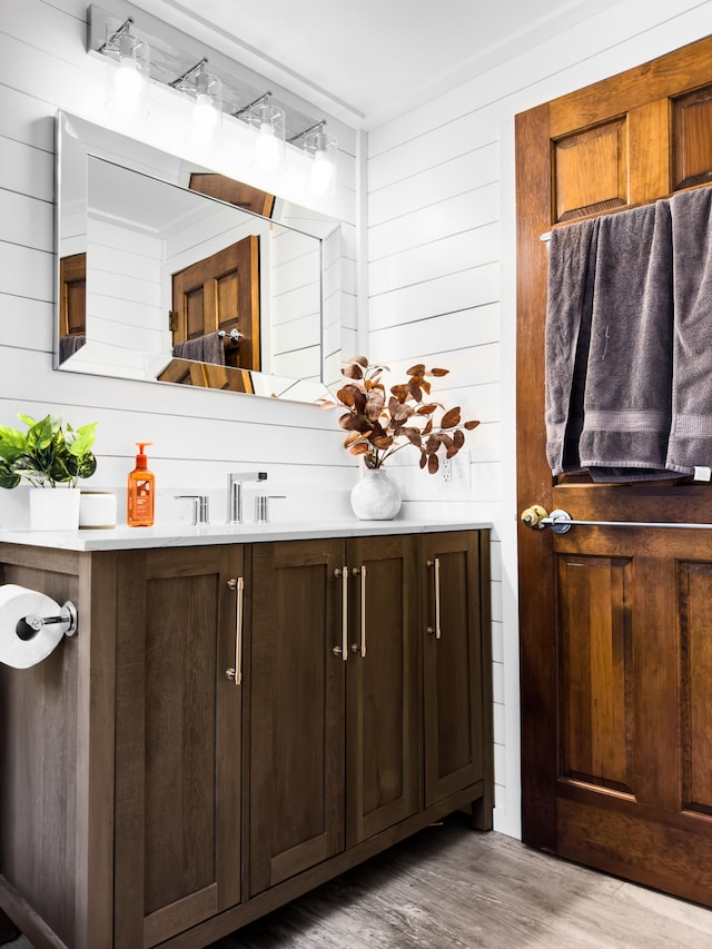 bathroom featuring wooden walls, vanity, and hardwood / wood-style flooring