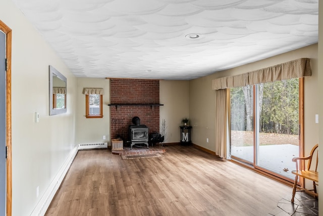 unfurnished living room with light wood-type flooring, a baseboard radiator, and a wood stove