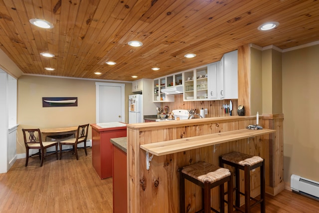 kitchen featuring a baseboard heating unit, light wood-type flooring, white fridge, white cabinetry, and a breakfast bar area