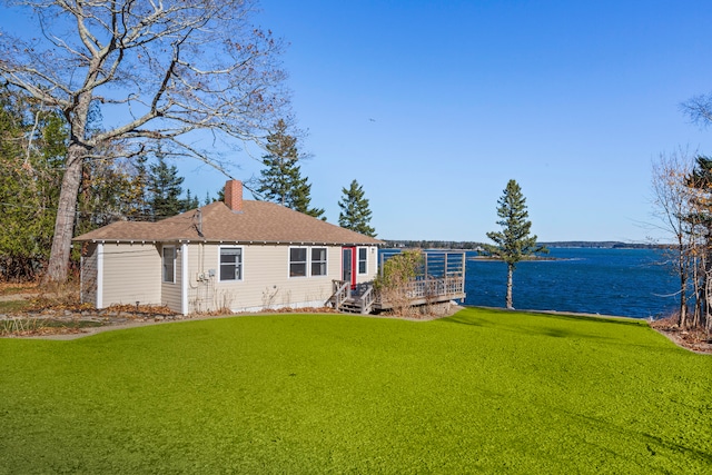 rear view of house featuring a deck with water view and a lawn