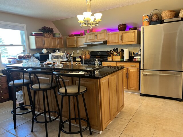 45 Douglas Dr, Newport, ME 04953 - kitchen featuring freestanding refrigerator, black gas range, under cabinet range hood, light tile patterned floors, and a chandelier