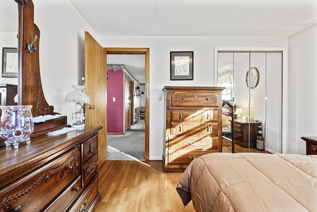 bedroom with a textured ceiling, light wood-type flooring, and a closet