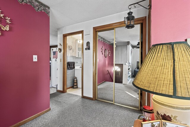 hallway with a textured ceiling and carpet floors